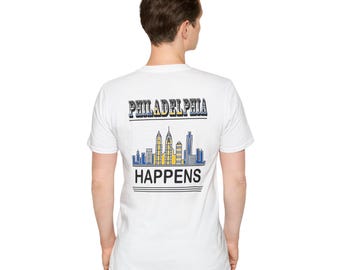 May include: White t-shirt with the text "PHILADELPHIA HAPPENS" in black, blue, and yellow. The design includes a skyline graphic. The shirt is made of a soft material.