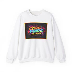 May include: White sweatshirt featuring a colourful graphic print that reads "CODE MODE: ACTIVATED" in a comic book style.
