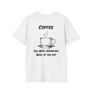 May include: White t-shirt featuring a black illustration of a coffee cup and saucer. The text above the cup says "COFFEE", and below it, "THE MOST IMPORTANT MEAL OF THE DAY". The design is a simple, sketched style.