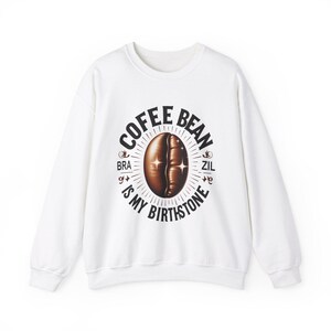 Puede incluir: Sudadera blanca con un estampado gráfico negro de un grano de café con el texto "Coffee Bean is My Birthstone" y las palabras "Bra" y "Zil" a cada lado del grano.