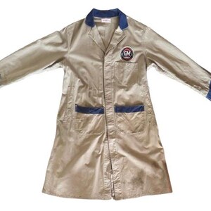 May include: A long-sleeved beige workwear jacket with blue trim and a patch on the left chest that says "GM".