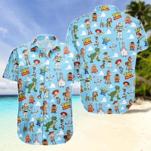 Puede incluir: Camisa abotonada azul claro con un patrón repetido de personajes de Toy Story y las palabras "Toy Story". La camisa de manga corta tiene un cuello clásico y cierre de botones. El fondo es azul claro con nubes blancas.