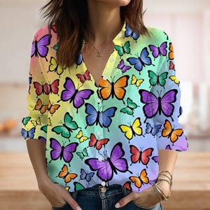 May include: A button-down shirt with a vibrant butterfly print. The shirt features a V-neck and long sleeves. The butterflies are in various colors, including purple, orange, yellow, and green, set against a rainbow gradient background.