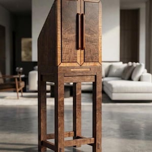May include: A tall, dark brown wooden cabinet featuring two vertical doors with prominent grain patterns, a slanted top section with slatted side detailing, and a sturdy four-legged base with horizontal support beams connecting the legs.