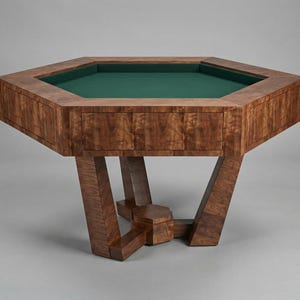 May include: A large, octagonal wooden table with a green felt playing surface. The table has a rich, dark wood grain finish and angled legs, creating a modern, geometric design. The table is suitable for games.
