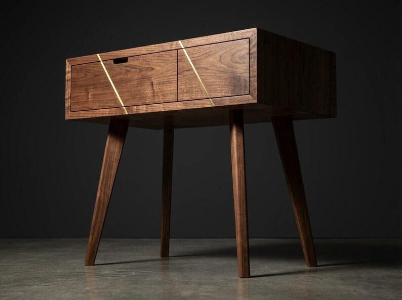 May include: A dark brown wooden side table featuring two drawers with a visible grain pattern. The front of the drawers is accented by two thin, diagonal gold-colored metal inlays that create a geometric pattern across the drawer faces.