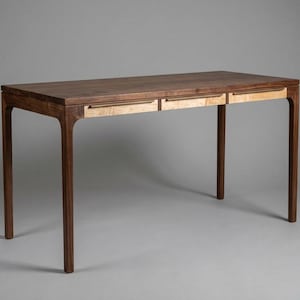 May include: A wooden desk with a dark brown top and legs, featuring two light-colored drawers. The desk has a rectangular shape and a minimalist design, suitable for a home office or workspace.