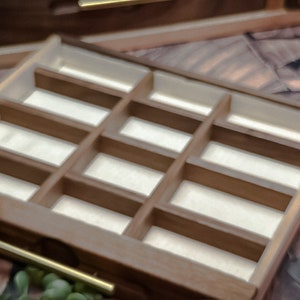 May include: A wooden box with a drawer that has multiple compartments. The drawer is open and the compartments are empty.