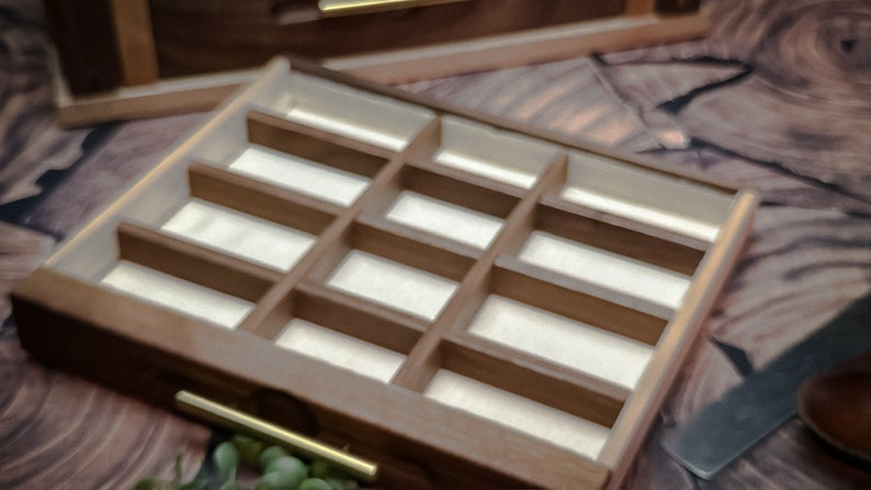 May include: A wooden box with a drawer that has multiple compartments. The drawer is open and the compartments are empty.
