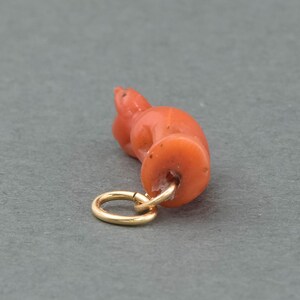May include: A coral pendant in the shape of a crouching cat with a gold jump ring.