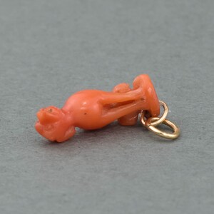 May include: A coral pendant in the shape of a stylized bird with a gold jump ring.