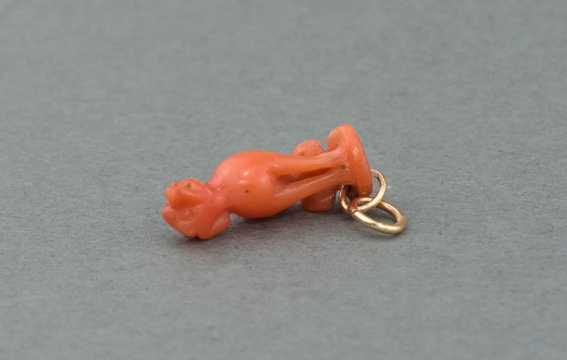 May include: A coral pendant in the shape of a stylized bird with a gold jump ring.