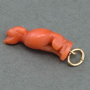 May include: A coral pendant in the shape of a stylized bird with a gold jump ring.
