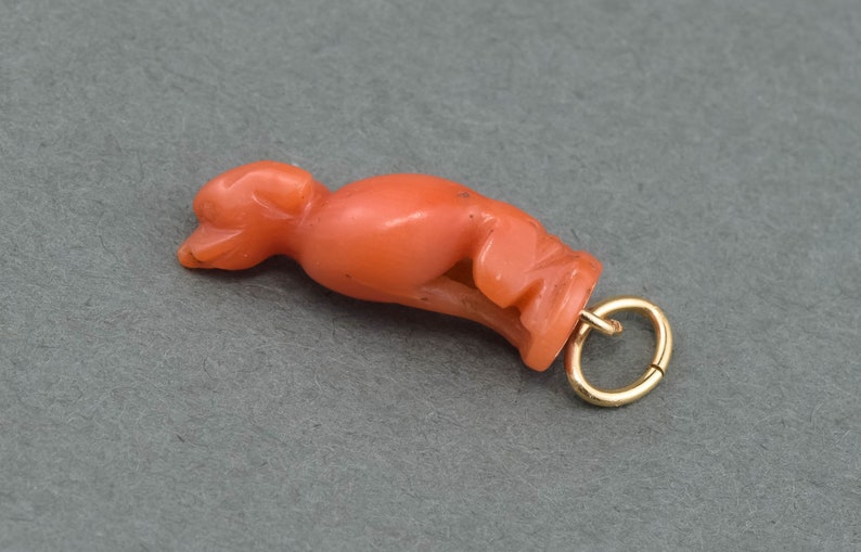 May include: A coral pendant in the shape of a stylized bird with a gold jump ring.