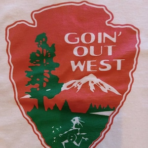 May include: White t-shirt with a red, green, and white graphic of a mountain range, a tree, and a person running. The graphic is in the shape of a National Park Service arrowhead and says "Goin' Out West".
