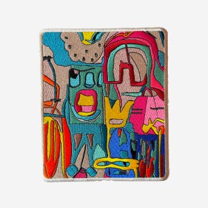 May include: Embroidered patch with a colorful abstract design. The patch features a variety of shapes and colors, including blue, red, yellow, and pink. The patch has a beige border and is rectangular in shape.