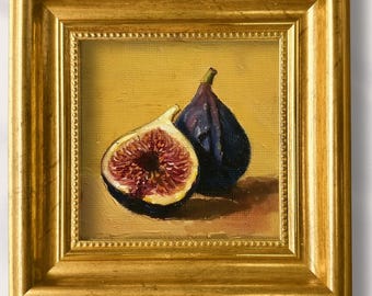May include: A framed, hand-painted still life featuring two figs. One fig is whole, the other is sliced, revealing the red interior. The artwork is in a gold frame, with the text "Lynn" and "100% Hand-Painted" above the frame.