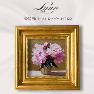 Puede incluir: Pintura cuadrada enmarcada en oro de peonías rosas en un jarrón. La obra de arte está pintada a mano y presenta el texto "Lynn" en escritura cursiva encima de la pintura, con "100% Hand-Painted" debajo.