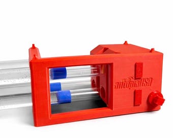 May include: A red plastic ant farm with clear tubes and blue stoppers. The ant farm has the text "antopiaUSA" on the side. The design includes a red knob and rectangular features.