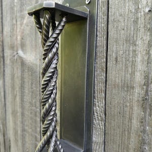 May include: A metal door handle with a twisted design. The handle is attached to a rectangular metal plate.
