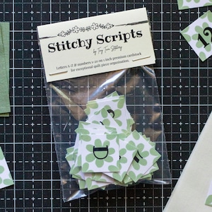 May include: A package of "Stitchy Scripts" quilt organization cards. The cards are white with a green floral design and black numbers and letters. The package includes letters A-Z and numbers 1-20 on 1-inch premium cardstock.