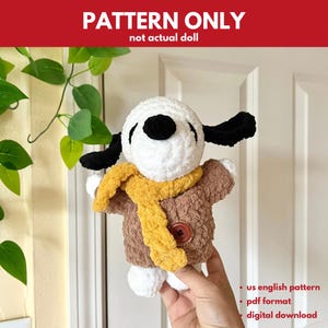 May include: A crocheted Snoopy doll, featuring a white head, black ears and nose, wearing a brown jacket and yellow scarf. The image includes the text "PATTERN ONLY" and "not actual doll".