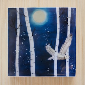 Può includere: Un gufo delle nevi vola attraverso una foresta blu scuro con betulle bianche e una luna piena sullo sfondo. Il gufo è bianco con occhi neri e un becco giallo.