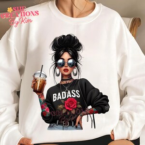 Puede incluir: Sudadera blanca con un estampado gr&aacute;fico de una mujer con gafas de sol, un collar negro y una rosa roja. El texto "BADASS" est&aacute; impreso en la camiseta.
