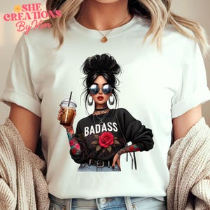 Puede incluir: Camiseta blanca con un gr&aacute;fico de una mujer con gafas de sol y una sudadera negra que dice "BADASS" con una rosa roja. La mujer est&aacute; sosteniendo una taza de caf&eacute;.