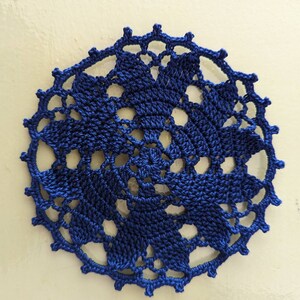 May include: A blue crocheted doily with a delicate floral pattern.