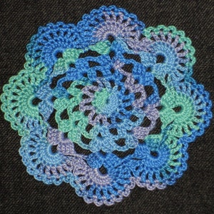 May include: A blue, green, and purple crocheted doily with a circular design.