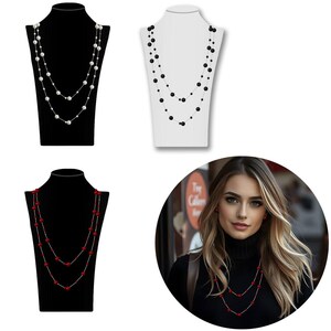 May include: Three necklaces are shown: one with white pearls, one with black beads, and one with red beads. The necklaces are displayed on black and white busts. A woman wears a red beaded necklace.