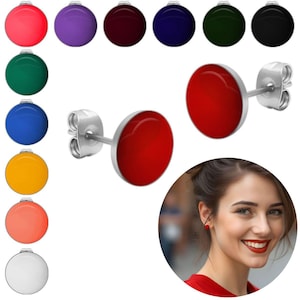 Könnte beinhalten: Rote Ohrstecker mit silberfarbenem Rand und Stecker. Das Bild zeigt auch eine Vielzahl anderer farbiger Ohrstecker, darunter rosa, lila, bordeaux, marineblau, grün und schwarz. Eine Frau trägt einen roten Ohrring.
