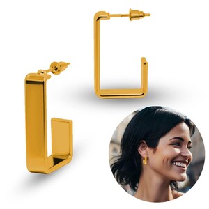 May include: A pair of gold-toned rectangular hoop earrings with a smooth, polished finish. Each earring features a post-back closure mechanism. The design consists of a continuous, open-ended rectangular frame that sits flush against the earlobe.