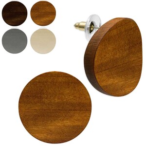 Könnte beinhalten: Ein runder Ohrstecker aus Holz mit einer mittelbraunen Holzmaserung. Der Ohrstecker verfügt über einen Metallstift und einen transparenten Kunststoffverschluss. Weitere Farboptionen sind im Hintergrund dargestellt, darunter dunkelbraun, hellbraun, grau und cremefarben.
