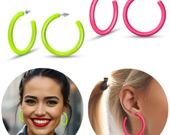 Puede incluir: Un par de pendientes de aro de color rosa brillante y un par de pendientes de aro de color verde brillante. Los pendientes son grandes y gruesos, y están hechos de un material liso y brillante. Los pendientes se muestran sobre un fondo blanco, y también se muestran puestos por una persona.
