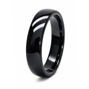 Op de afbeelding: Een glanzende zwarte ring met een glad, afgerond ontwerp. De ring reflecteert licht en creëert heldere witte highlights. Het sieraad staat tegen een effen witte achtergrond.