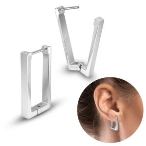 May include: Two silver-coloured, geometric hoop earrings. One earring is open, displaying the post and clasp. The other earring is closed, showing a rectangular shape. The earrings are shown next to an ear wearing a similar earring.