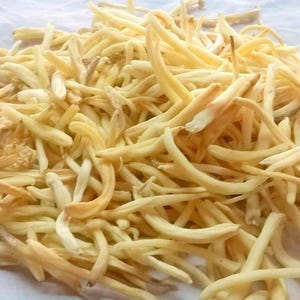 May include: A pile of dried white flower buds, resembling thin, pale noodles. The buds are light yellow and cream colored, with a slightly rough texture.