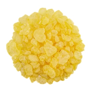 May include: A close-up of a pile of yellow resin pieces. The resin is translucent and has a slightly irregular shape.