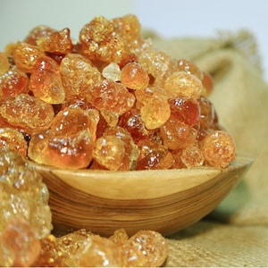 Peut inclure: Un bol en bois rempli de gomme arabique de couleur ambre, une résine naturelle utilisée dans l'alimentation et les cosmétiques.