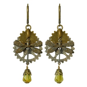 May include: A pair of steampunk-style earrings. Each earring features a dragonfly charm over a gear-shaped base, with a teardrop-shaped green bead dangling below. The earrings are made of bronze and silver-toned metal.