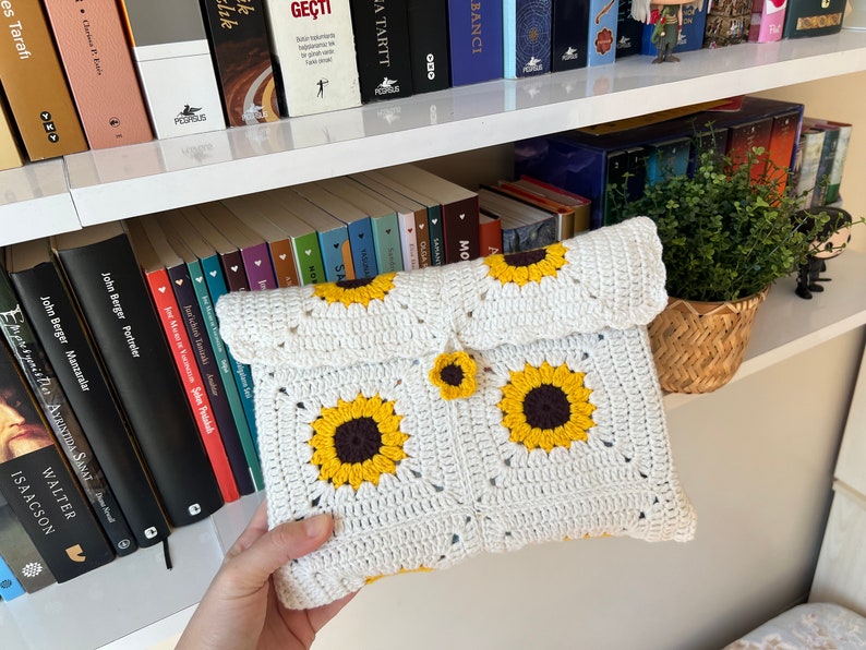 Puede incluir: Clutch blanca de crochet con dise&ntilde;o de girasol. La bolsa tiene cierre de solapa y un peque&ntilde;o bot&oacute;n de girasol.