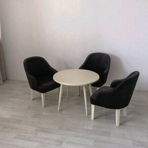 Peut inclure: Une table ronde blanche avec trois chaises noires. Les chaises ont un design simple avec un dossier arrondi et des pieds blancs.