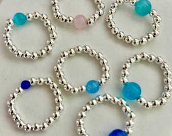 Anillos llamativos bañados en plata. Elaborados con bonitas cuentas y divertidos dijes.