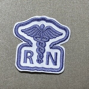 May include: Embroidered patch featuring a Caduceus symbol and the letters "R N" in blue on a white background. The patch has a blue border and is designed for medical professionals, specifically Registered Nurses.