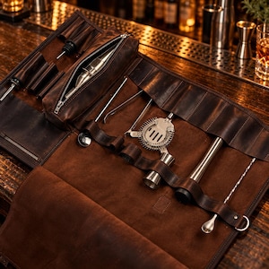 May include: A dark brown leather bartender roll-up bag containing stainless steel bar tools including a Hawthorne strainer, a muddler, a jigger, a long mixing spoon, metal tongs, and bottle pourers, all secured within individual leather slots and a zippered pouch.