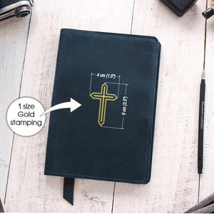 May include: A dark blue leather-bound journal with a gold cross embossed on the front cover. The cross is 1.5 inches wide and 2.5 inches tall. The journal has a black ribbon bookmark.