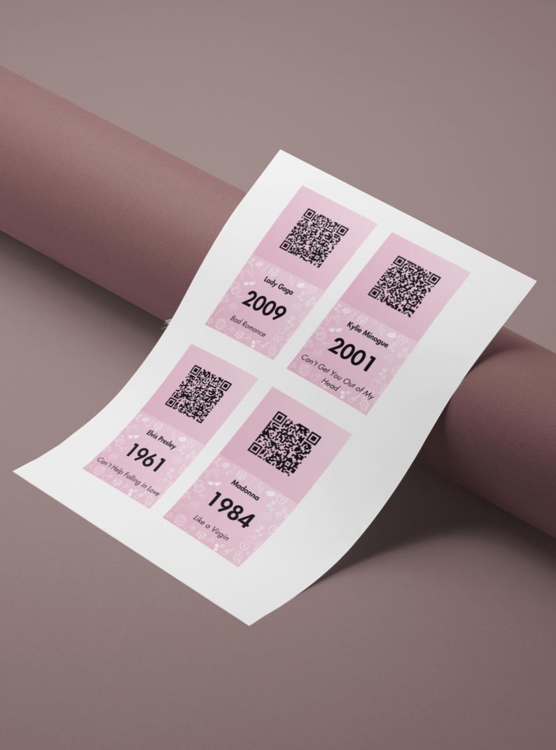 May include: A sheet of paper with four pink and white rectangular designs, each featuring a QR code and text. The text includes artist names like Lady Gaga and Madonna, along with song titles and years such as 2009 and 1984.