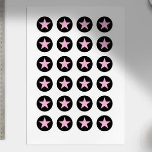May include: A white sheet with a repeating pattern of black circles, each with a pink star. The circles are arranged in a grid. The stars are a lighter shade of pink. The design is simple and symmetrical.